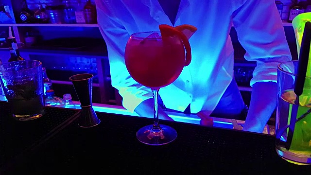 酒保准备红酒精鸡尾酒饮料在玻璃与柠檬片在迪斯科酒吧的桌子上，俱乐部气氛和乐趣视频下载