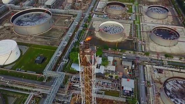 鸟瞰图化工或炼油厂与燃烧的火炬，储罐在日出的城市视频素材