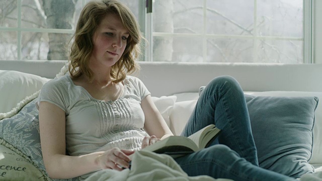 美国犹他州，Pleasant Grove，一个女人坐在靠近窗户的床上看书视频素材