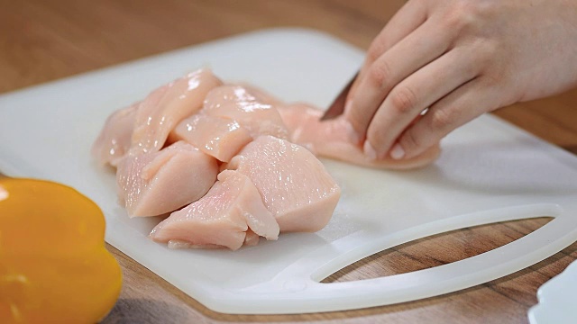 女厨师在切菜板上切生鸡肉。视频下载