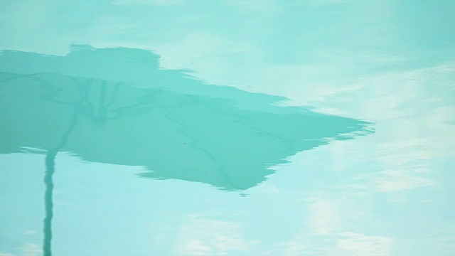 在欧洲意大利的豪华度假胜地，海滩伞在蓝色的游泳池中反射。——慢动作视频下载