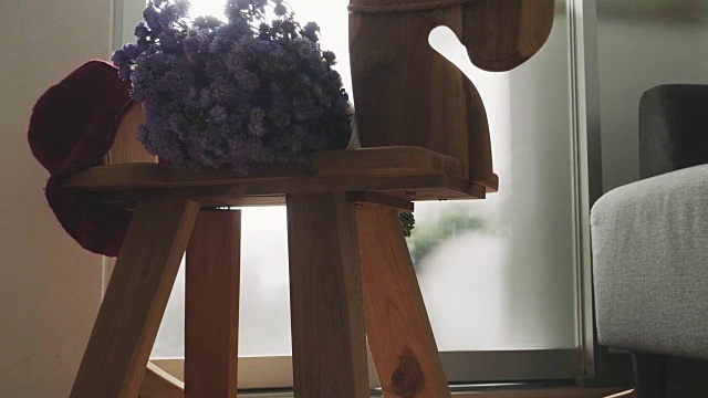 客厅的马凳上有紫罗兰花和红帽子视频素材