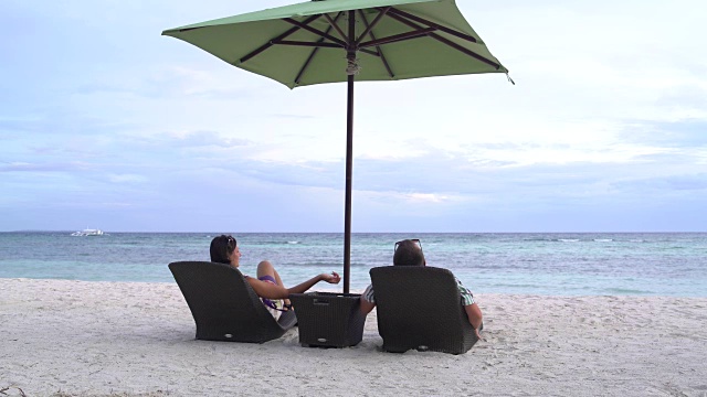 一个男人和一个女人躺在海边的躺椅上视频素材