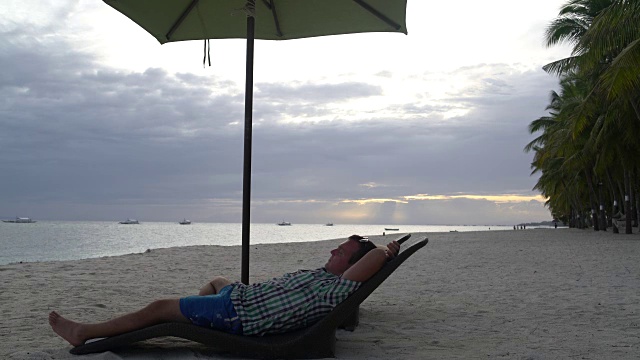 日落时，人们在海边的躺椅上休息视频素材