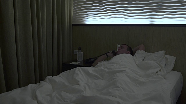 男人躺在床上，用座机打电话视频下载