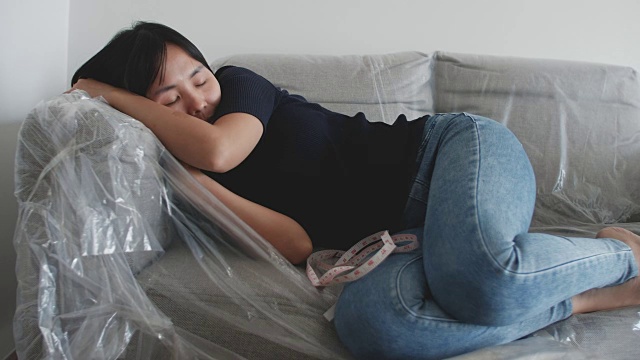 一个年轻女子耐心地躺在客厅的沙发上视频下载
