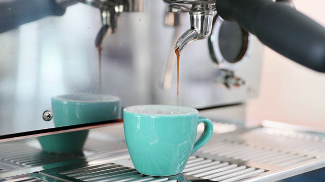 专业的咖啡机在绿薄荷杯制作浓缩咖啡。视频下载