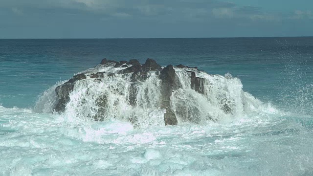 慢动作:强大的海浪溅过大海中央的一块大岩石视频素材