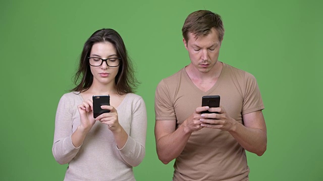 年轻夫妇在绿色背景下一起使用手机视频下载