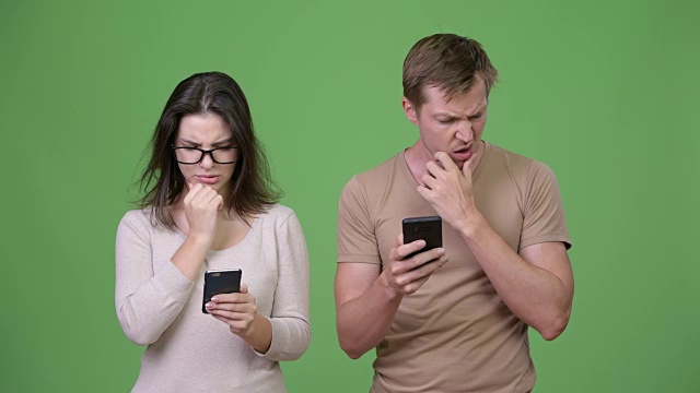年轻夫妇一边用手机一边思考视频下载