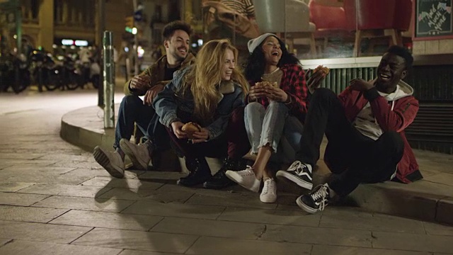 年轻的朋友们坐在人行道上大笑视频素材