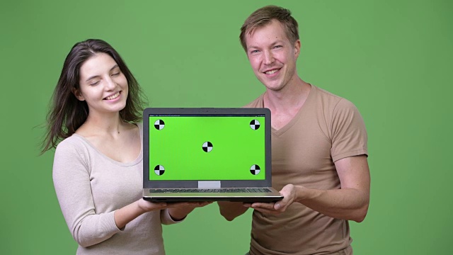 年轻幸福的夫妇在一起展示笔记本电脑时微笑视频下载