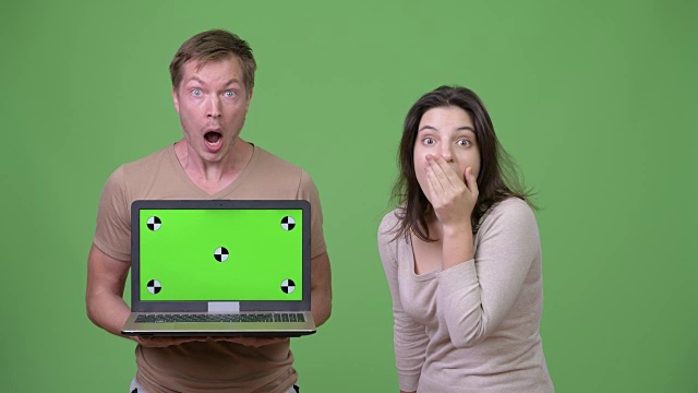 年轻夫妇展示笔记本电脑，同时看起来震惊在一起视频下载