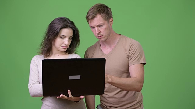 年轻夫妇使用笔记本电脑，一起思考视频下载