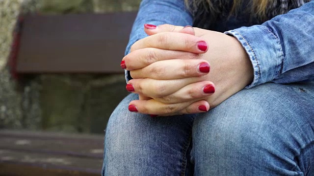 在秋天的公园里，一个女人坐在长椅上，双手紧张视频下载