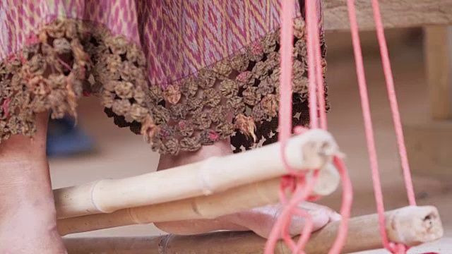 传统的泰国纺织业在手工艺村，老妇人在木制织布机上工作，纺纱制造棉织物。视频下载