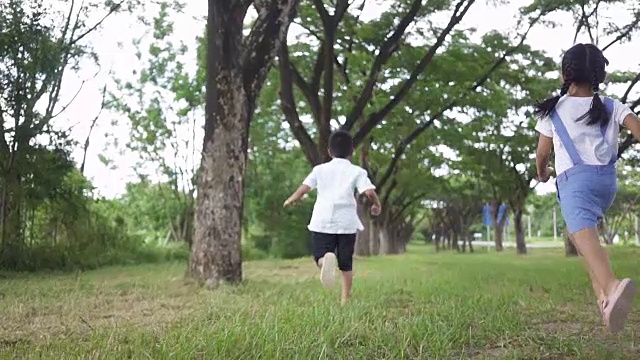 慢镜头，亚洲家庭，男孩和女孩在公园里跑步。视频素材