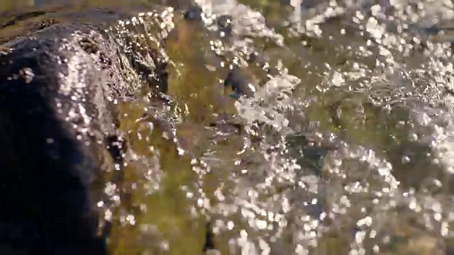 清澈的水流溅到岩石上。视频下载