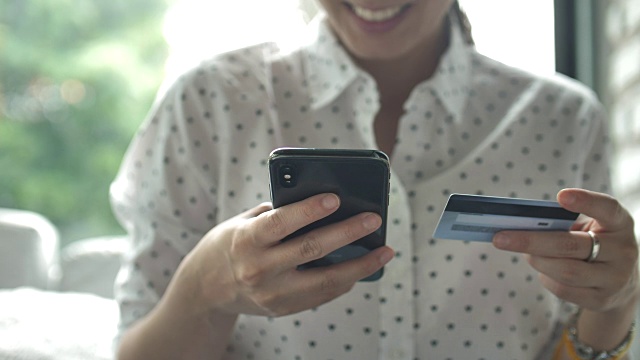 亚洲女人在智能手机上购物和使用信用卡视频素材