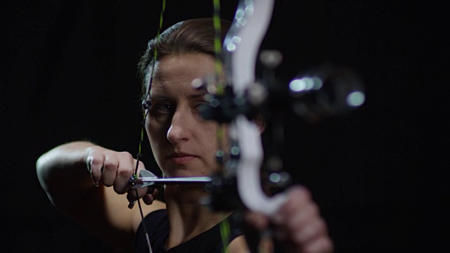 女射手射击弓对黑色的背景视频素材