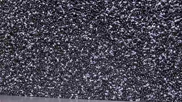 塑料黑灰色颗粒状的碎屑。生产塑料水管的工厂。用水和空气的压力在机床上制造塑料管的工艺。视频素材