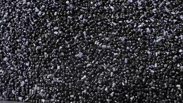 塑料黑灰色颗粒状的碎屑。生产塑料水管的工厂。用水和空气的压力在机床上制造塑料管的工艺。视频素材