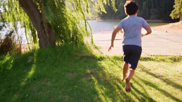 日落时分，两个孩子从车里跳下来，跑到湖边的码头视频素材