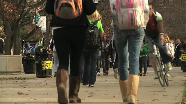 一大群学生在美国密歇根大学安娜堡校区的公园里散步视频下载