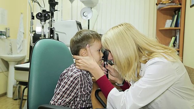 女儿科验光师正在检查小男孩的眼睛。视频素材
