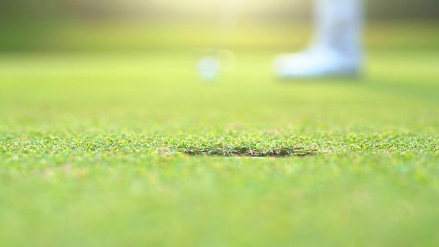 慢动作高尔夫球手把高尔夫球洞赢家在高尔夫球场是美丽的球道日落视频素材