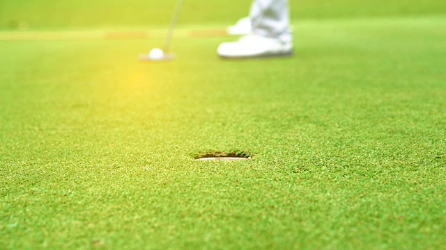 慢动作高尔夫球手把高尔夫球洞赢家在高尔夫球场是美丽的球道日落视频素材