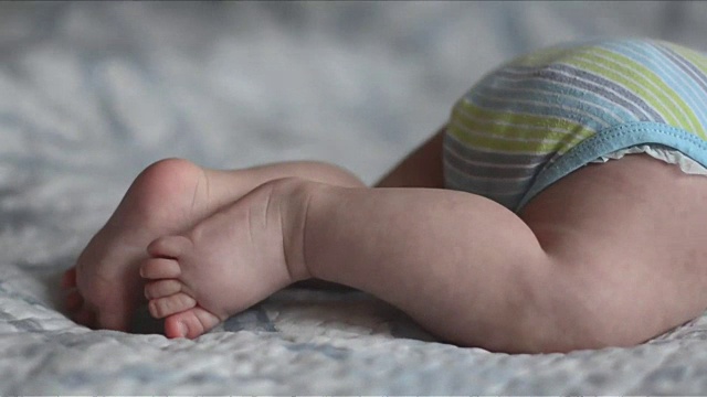 婴儿的脚试图爬躺在床上的特写视频下载