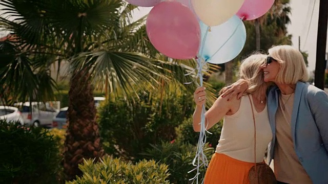 兴高采烈的老年妇女拿着气球走在城市里视频素材