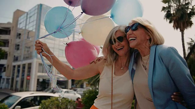 欢乐的成年妇女在城市里用气球庆祝视频素材