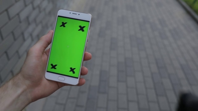 POV，男性手握智能手机绿屏在城市中行走视频素材
