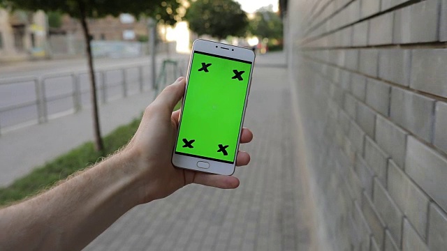 手持智能手机绿色屏幕的人在城市中行走视频素材