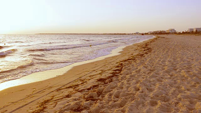 傍晚的海滩上，海浪拍打着沙滩。美丽的大海和天际线背景视频素材