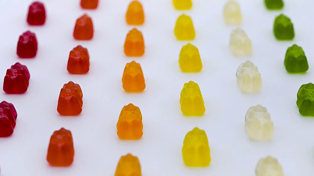 彩色的小熊软糖，甜蜜的水果果冻糖果行在白色的背景垂直移动视频素材