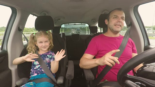 父亲和他的小女儿正在开车。父母和孩子开车，唱歌，跳舞视频素材