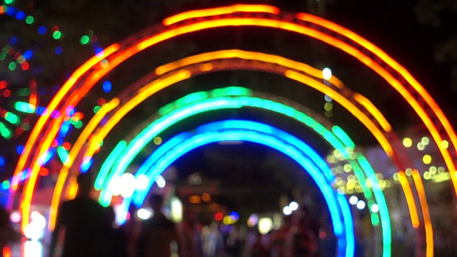 人们在游乐园的夜晚，以五颜六色的灯光为背景的现代景点。视频素材