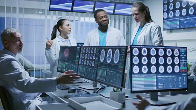 在大脑研究实验室工作的专业医学科学家团队。神经学家/神经科学家在CT, MRI扫描显示器的包围下热烈讨论。视频素材