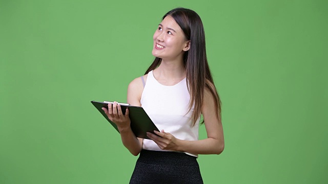 年轻美丽的亚洲女商人拿着写字板在思考视频下载