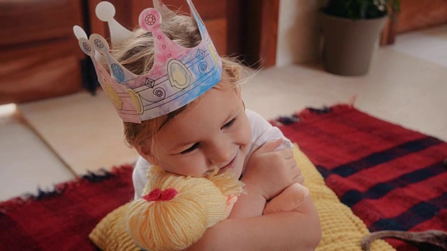 可爱的小女孩戴着公主帽玩洋娃娃视频素材