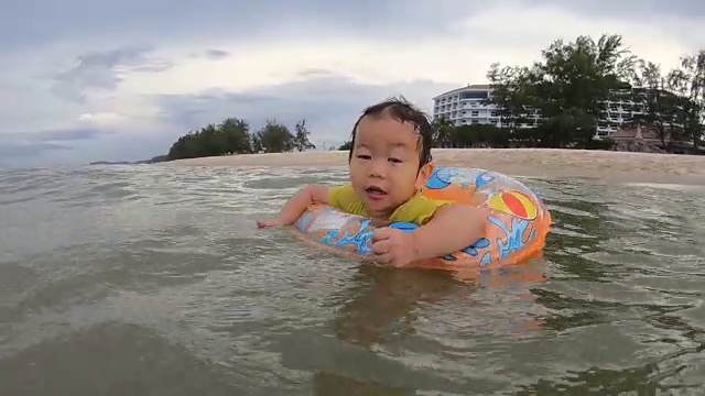 夏季游泳概念。亚洲男孩慢动作举起水玩和游泳。他戴着戒指视频素材