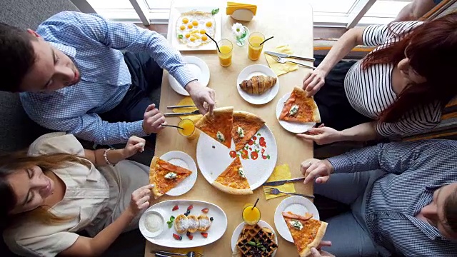 服务员在桌子上放了一个披萨给正在餐馆用餐的年轻朋友们视频素材