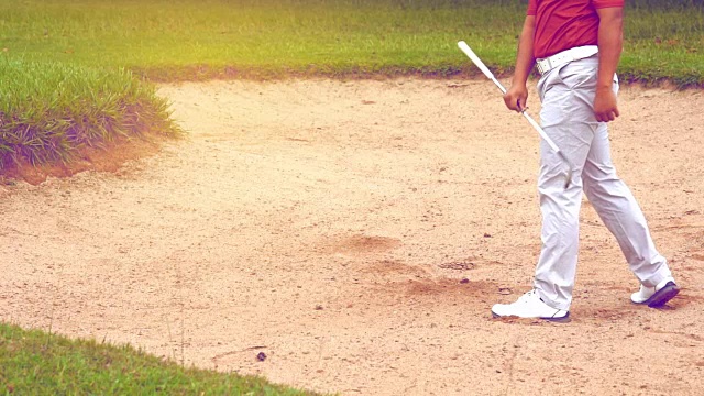 慢动作高尔夫概念，高尔夫球手在高尔夫球场打高尔夫球。选手在沙坑上慢速挥击球。视频素材