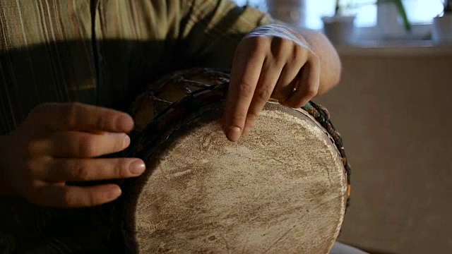 一个男人的手在一个非洲皮肤覆盖的手鼓上敲出一个节拍。视频素材
