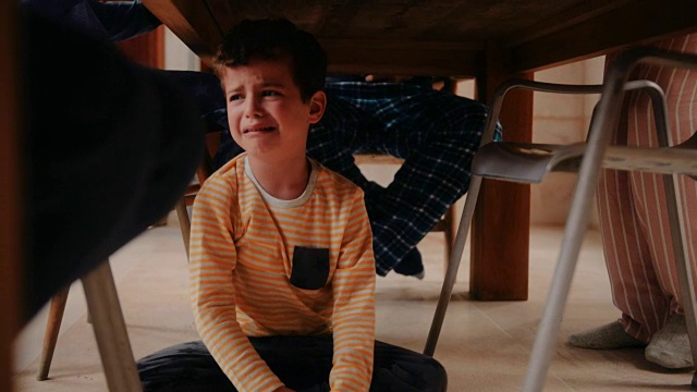 吃早餐时坐在餐桌下哭泣的男孩视频素材