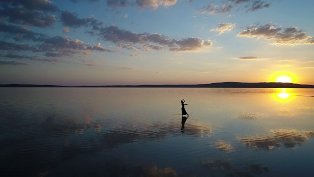 日落时，芭蕾舞演员在湖上跳舞。空中拍摄的视频素材