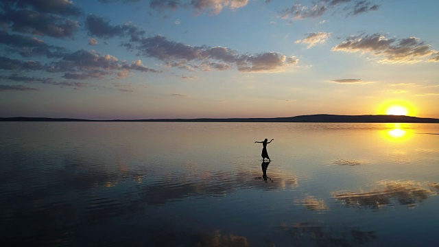 日落时，芭蕾舞演员在湖上跳舞。空中拍摄的视频下载